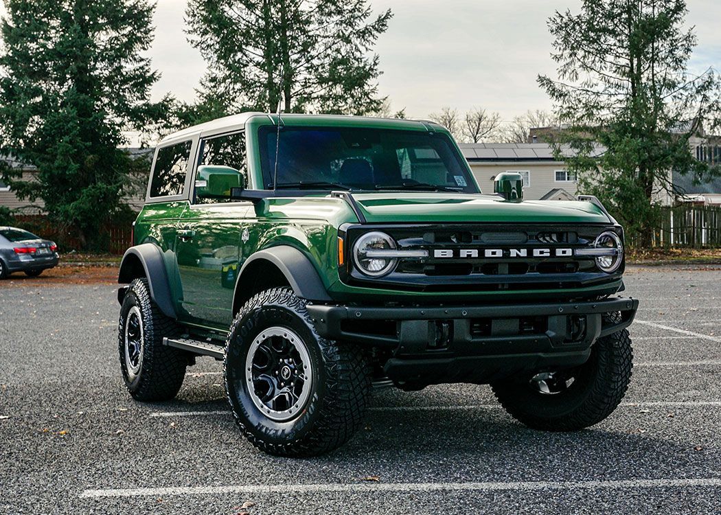 A green ford bronco is parked in a parking lot.