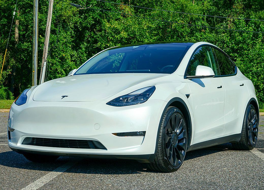 A white tesla model y is parked in a parking lot.