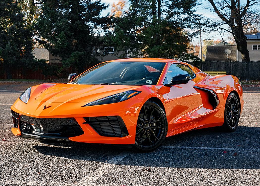 An orange sports car is parked on the side of the road.