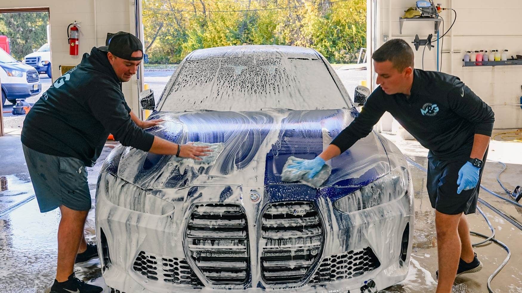 two men are washing a bmw in a garage