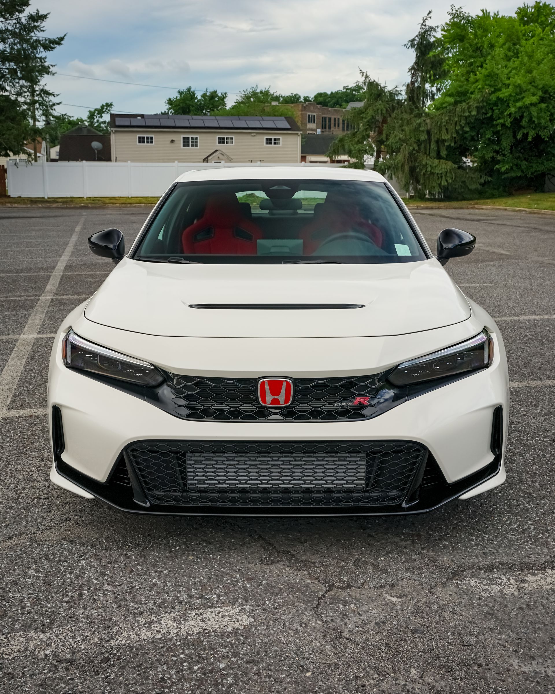 White Honda Civic Type R sports car, red accents, parked in a lot, overcast sky.