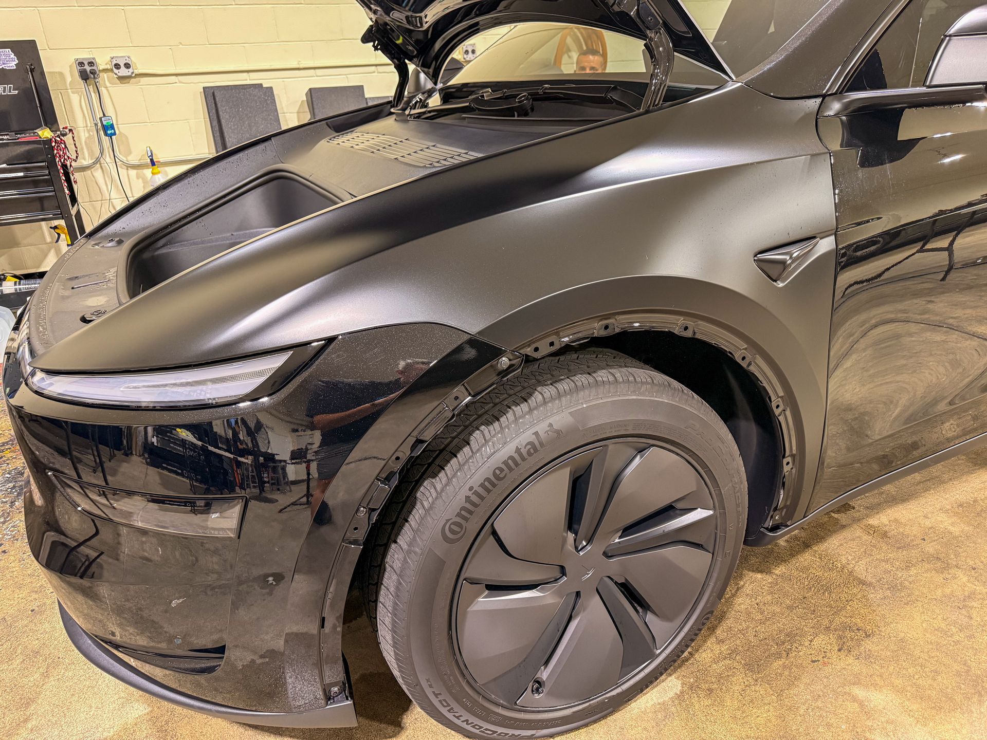 Black electric SUV parked indoors with its rear hatch open and front wheel turned slightly outward