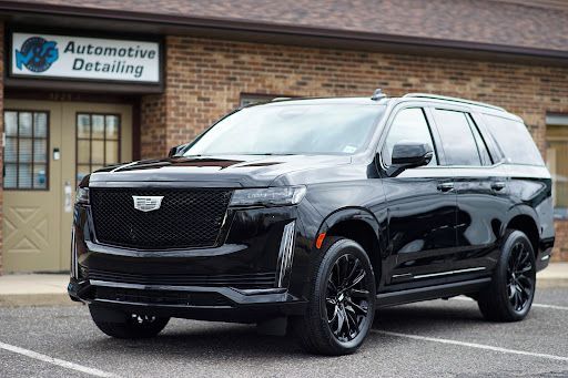Black Cadillac Escalade SUV with PPF paint protection film, photographed outside an automotive detailing shop