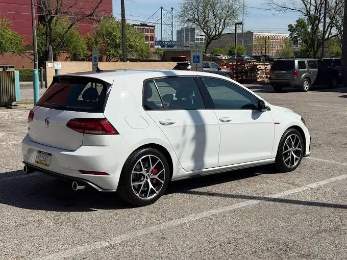 White Volkswagen Golf GTI with auto window tint parked in a lot
