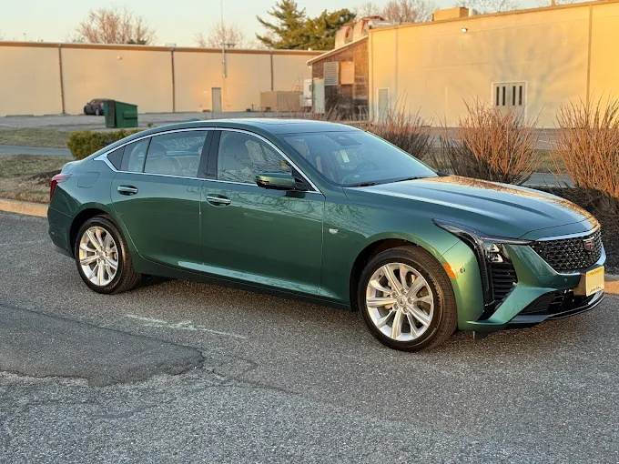 Green sedan parked outdoors beside a building at sunset