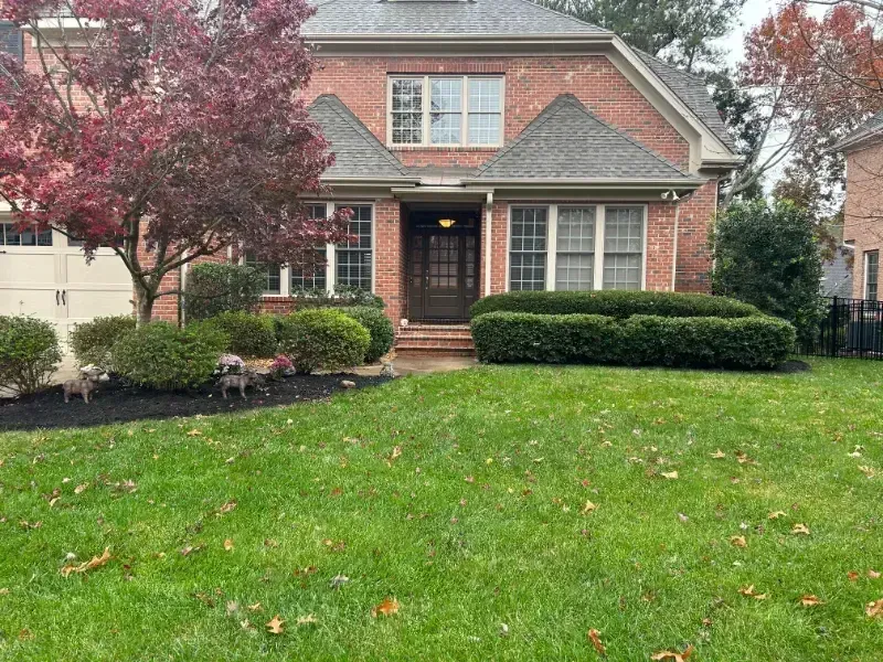 A large brick house with a lush green lawn in front of it.