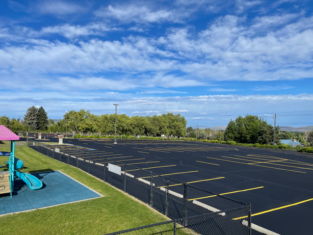 There is a playground in the middle of a parking lot.