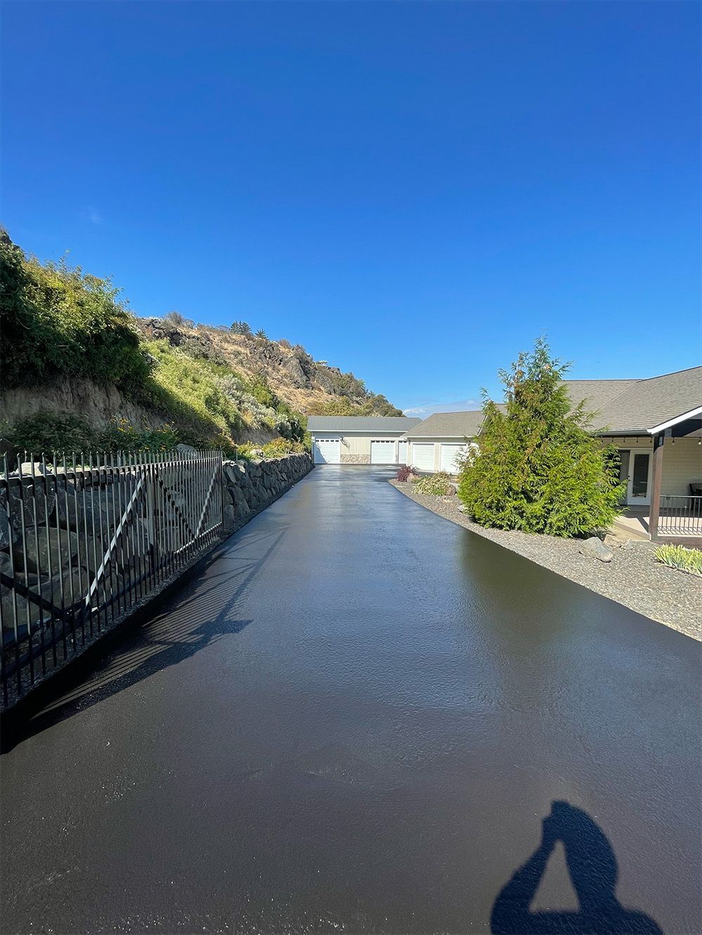 A driveway leading to a house with a fence along the side of it.