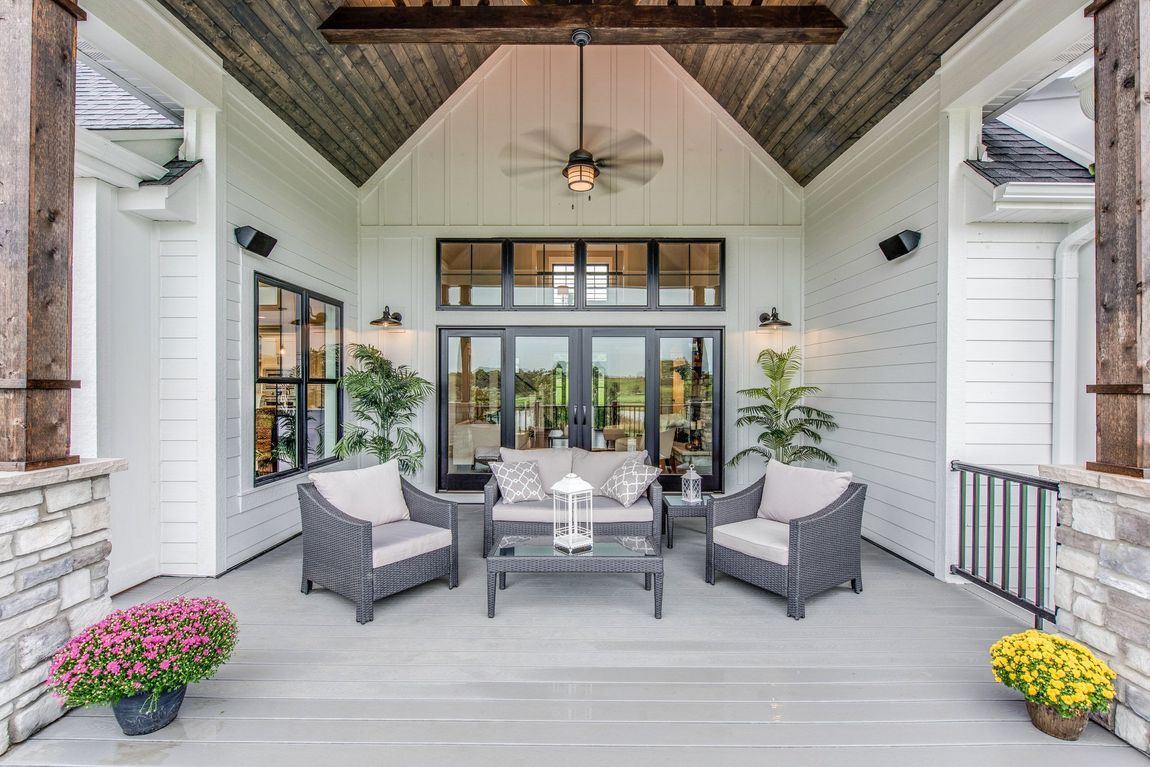 Outdoor covered patio with seating, plants, and black framed doors and windows.