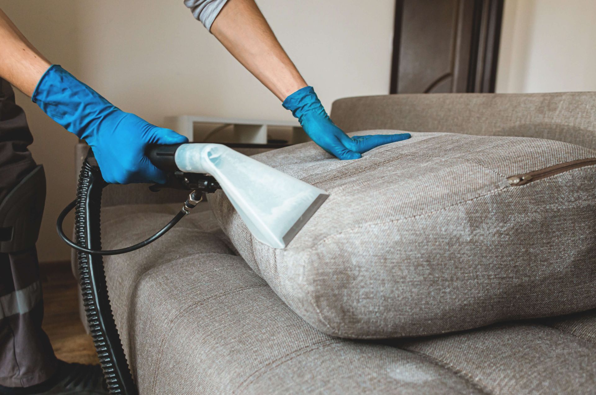 Professional upholstery cleaning service removing dirt and stains from a light grey fabric sofa