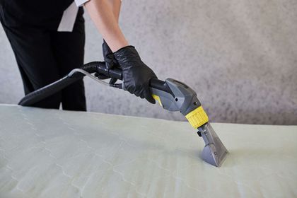 Person in black gloves using a cleaning machine on a light-colored surface.