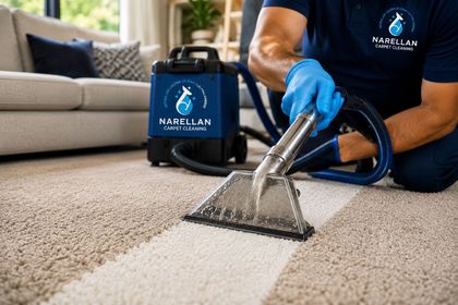 Person using carpet cleaner on beige carpet, wearing gloves.