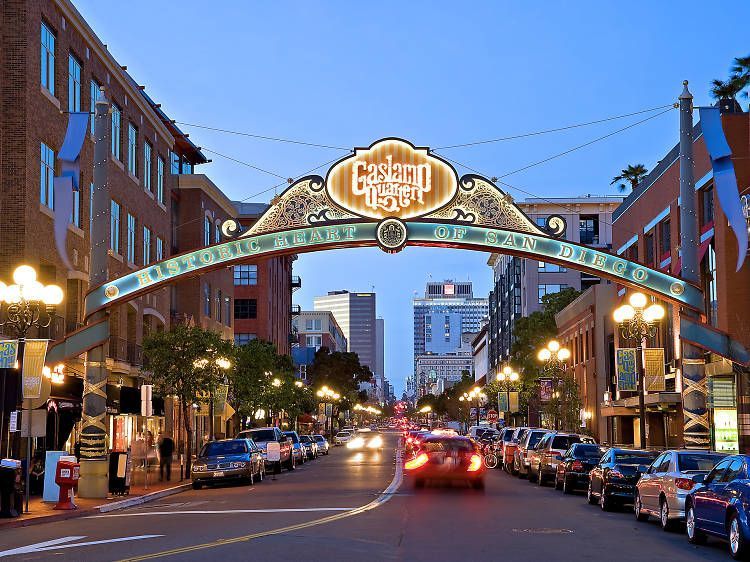 Gaslamp Quarter archway over a street lined with cars and buildings at dusk.
