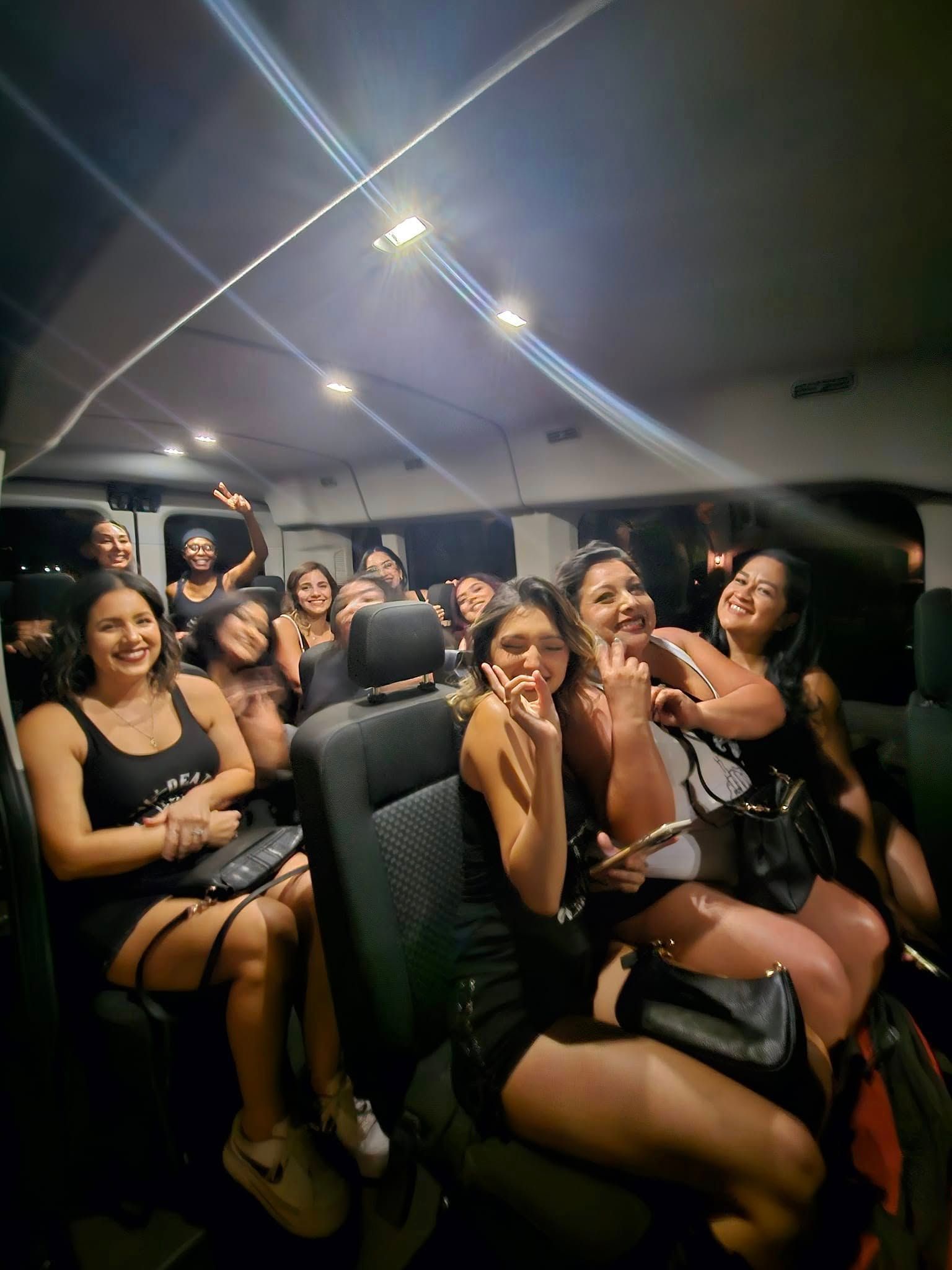 Group of people smiling and posing inside a van at night.