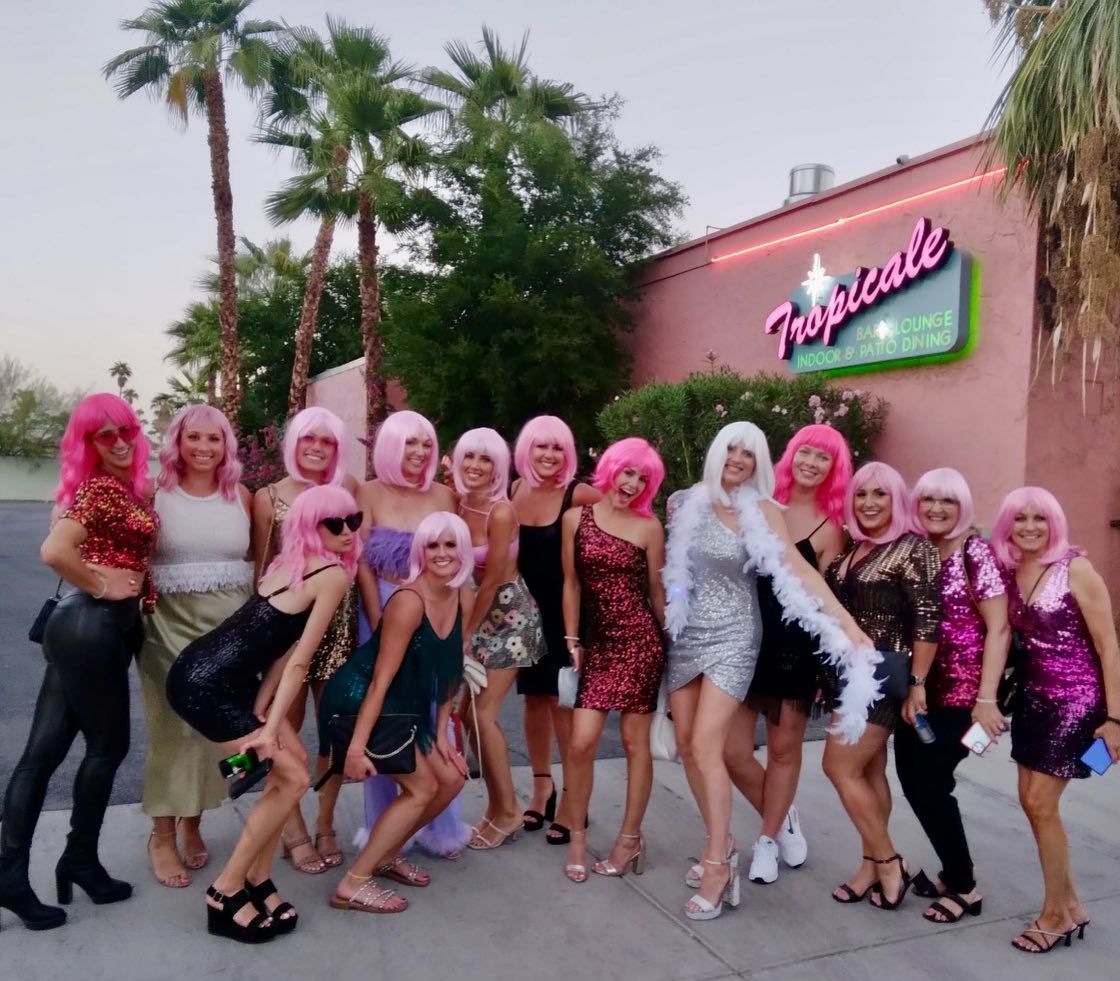 A group of women posing in front of a building that says tropicale
