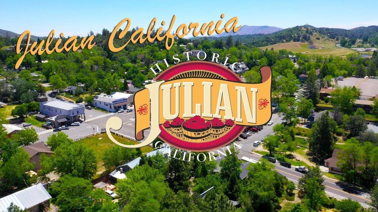 Aerial view of Julian, California with town logo overlay. Green trees, blue sky.