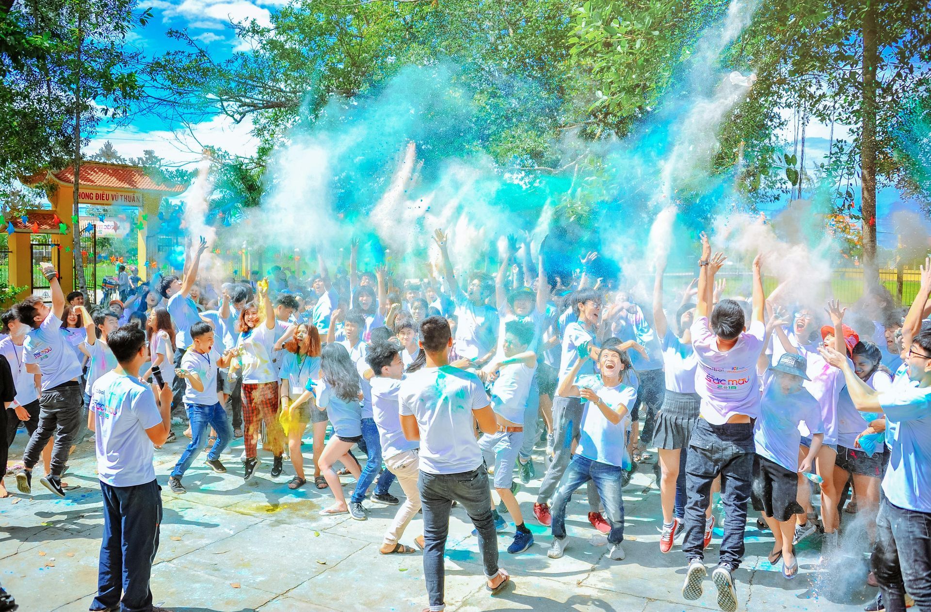 Group of people in white shirts throwing blue and white powder in the air.