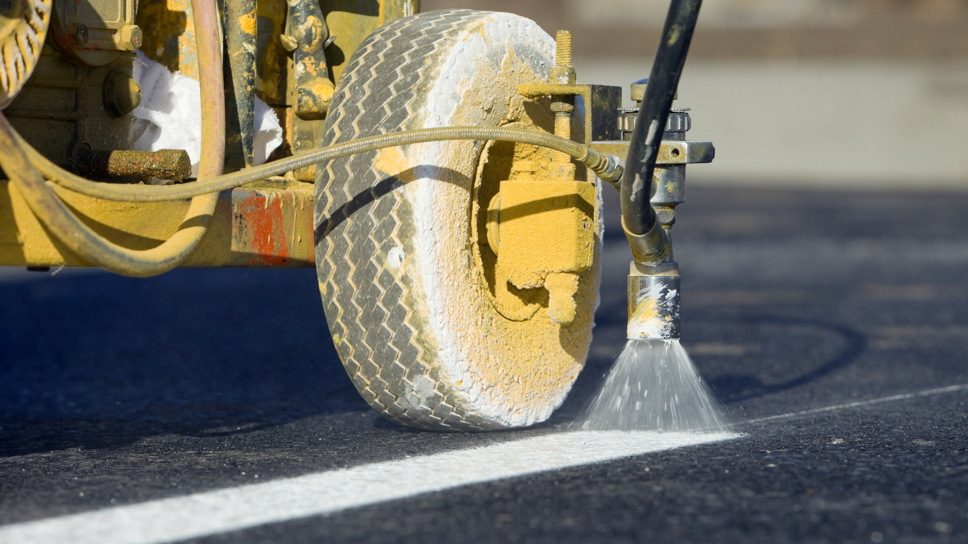 Yellow road-marking machine spraying white paint on asphalt to paint a lane line