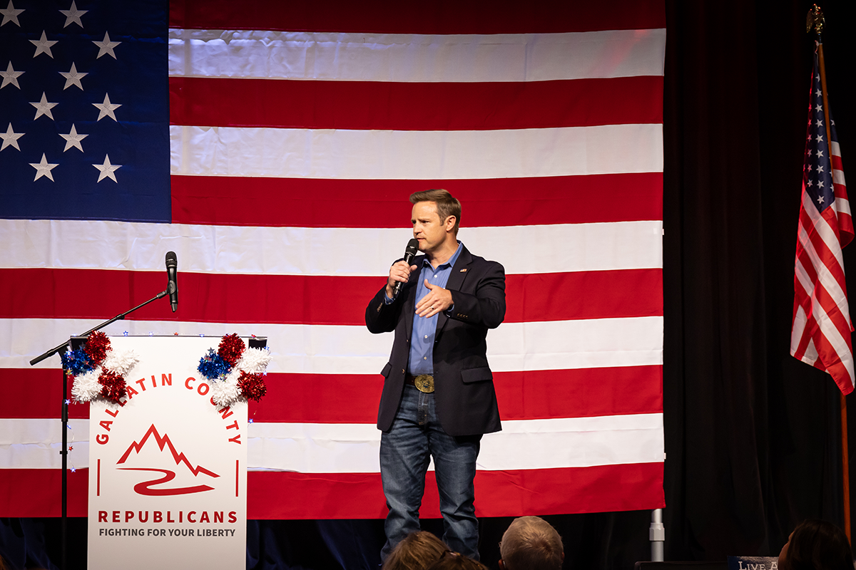 Speaker at podium in front of a large American flag at a Republican event