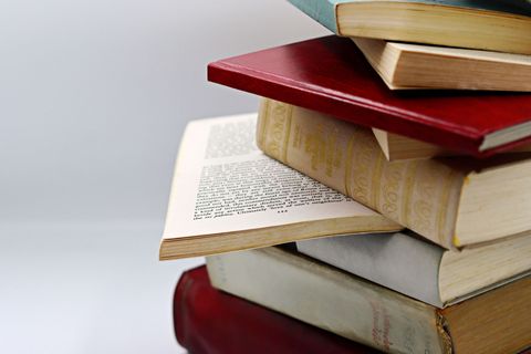 Stack of colorful books with an open book in the middle on a plain light background
