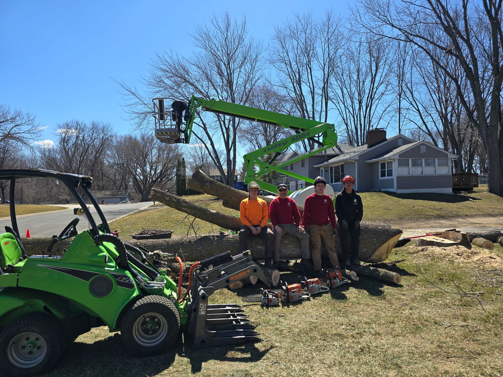 A group of men are standing in front of a green tractor - Shakope, MN - Your Tree Guy, LLC