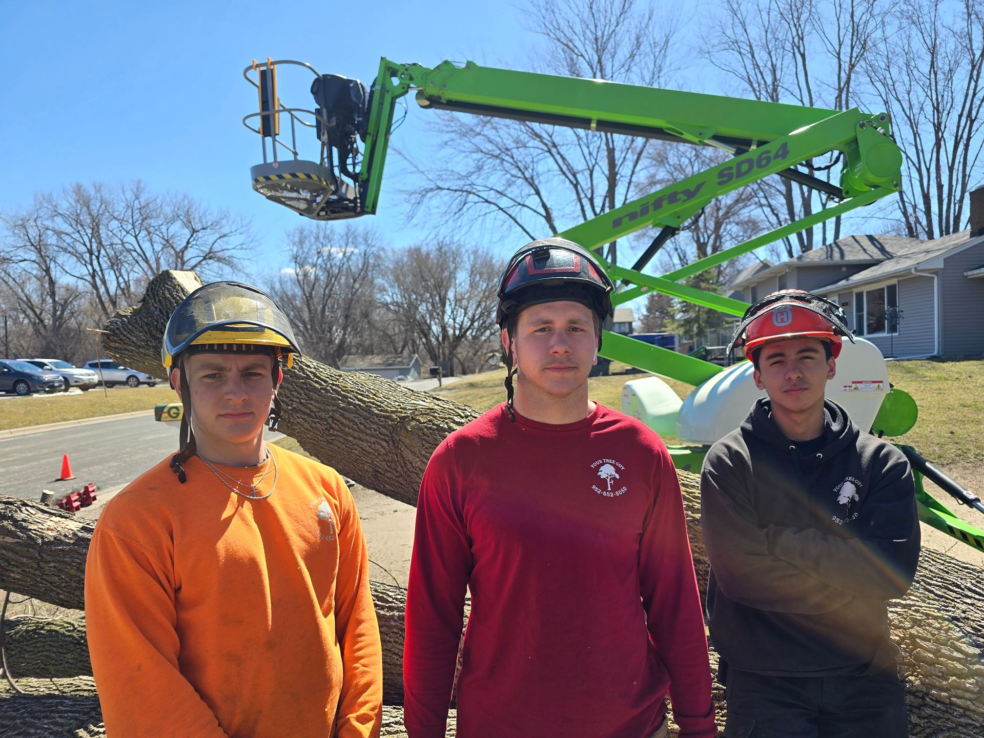 Three men are standing in front of a green crane - Shakope, MN - Your Tree Guy, LLC