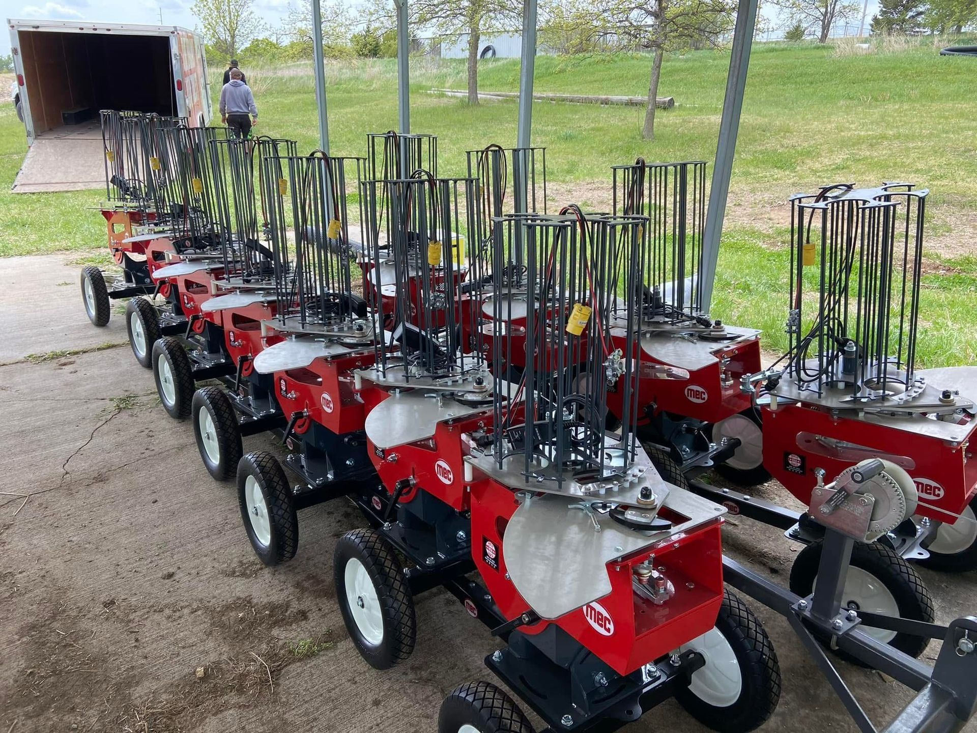 Red and black clay pigeon launchers lined up outdoors, under a covered area.