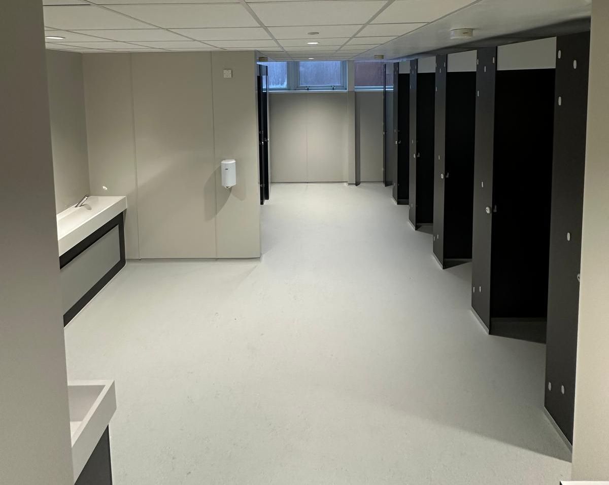 A long hallway filled with lockers and a sink.