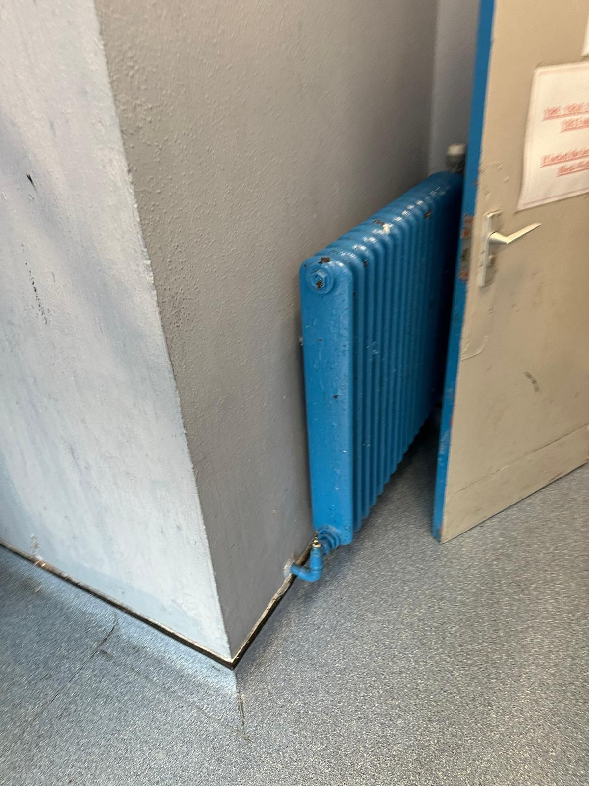 A blue radiator is sitting next to a door in a room.