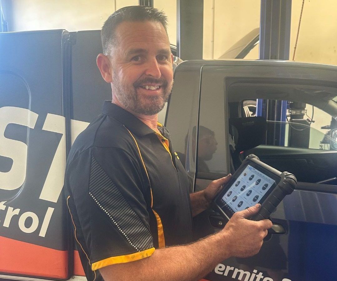 A Man is Holding a Tablet in Front of a Varsity Lakes Mechanical Truck — Varsity Lakes Mechanical Repairs In Varsity Lakes, QLD