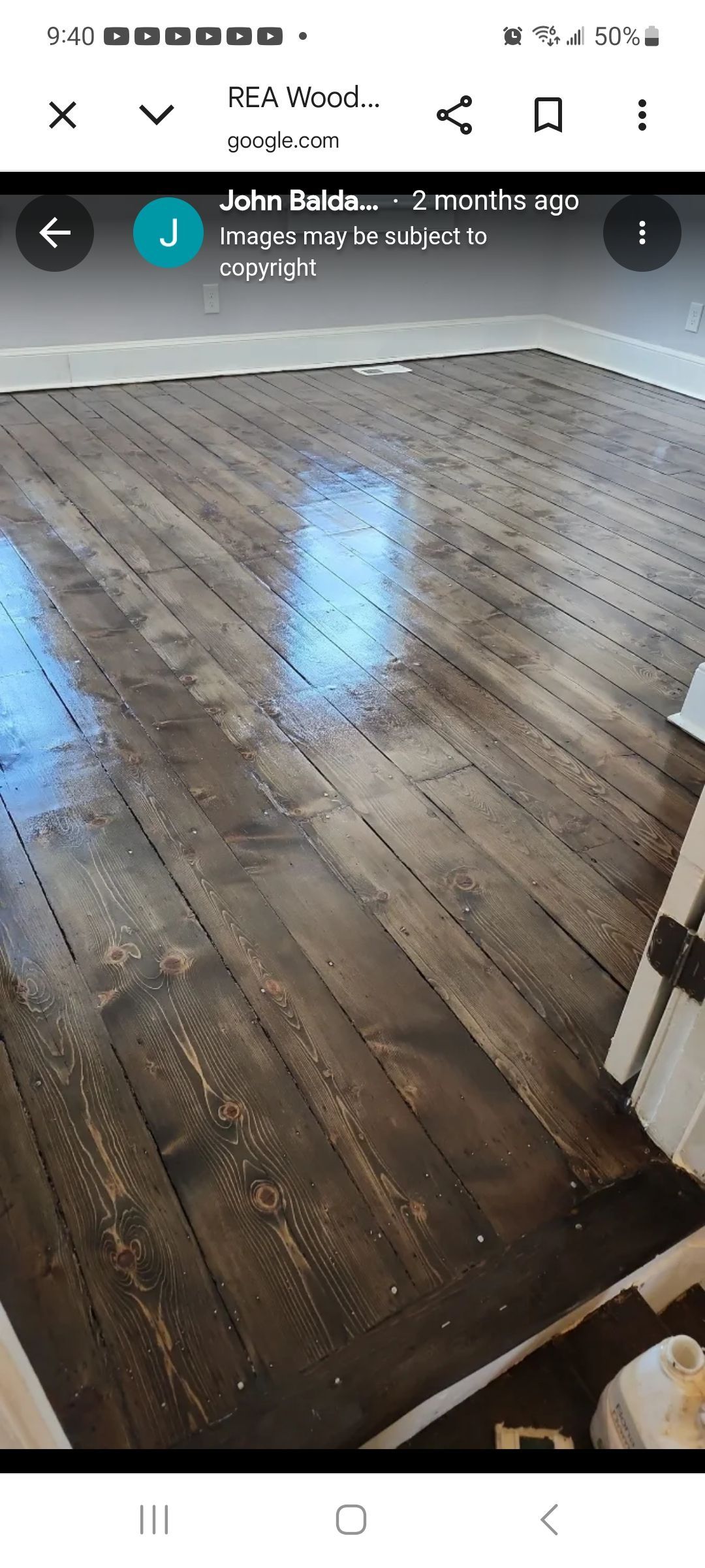 Hardwood floor hallway with pink and brown walls, leading to a kitchen with dark cabinets.