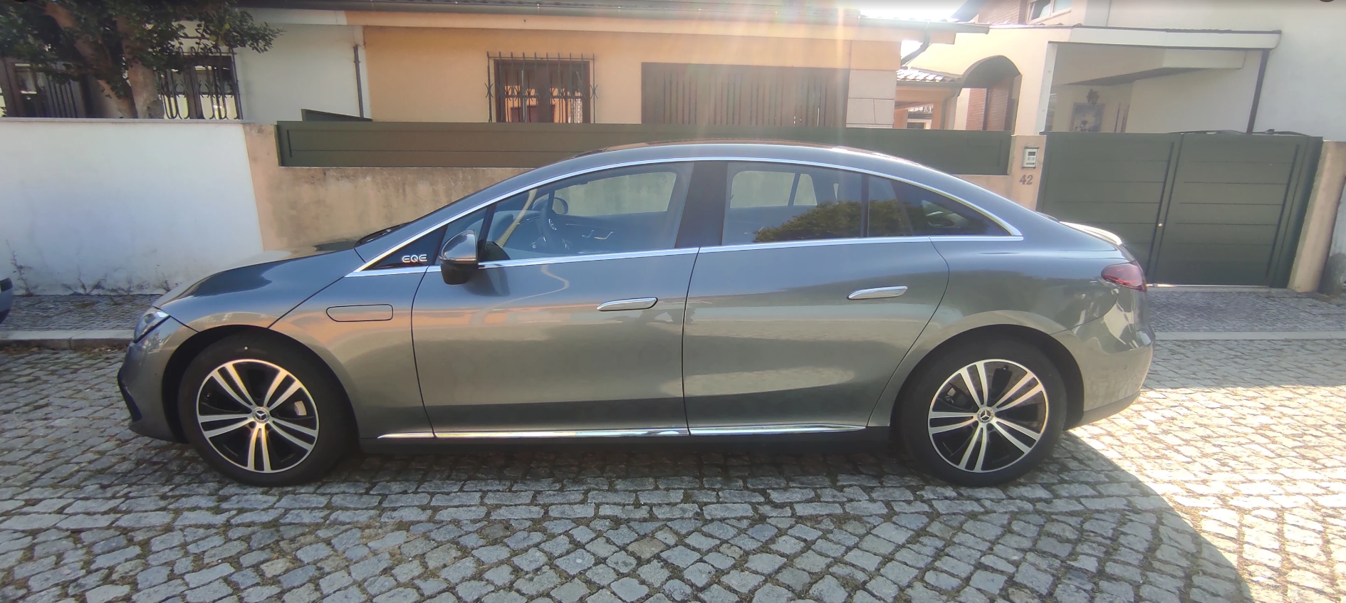 Sedã prateado estacionado na entrada de uma casa.