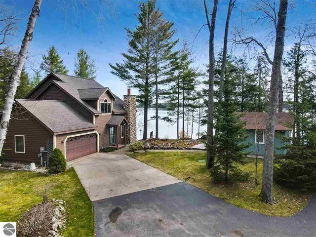A house with a garage and a driveway surrounded by trees