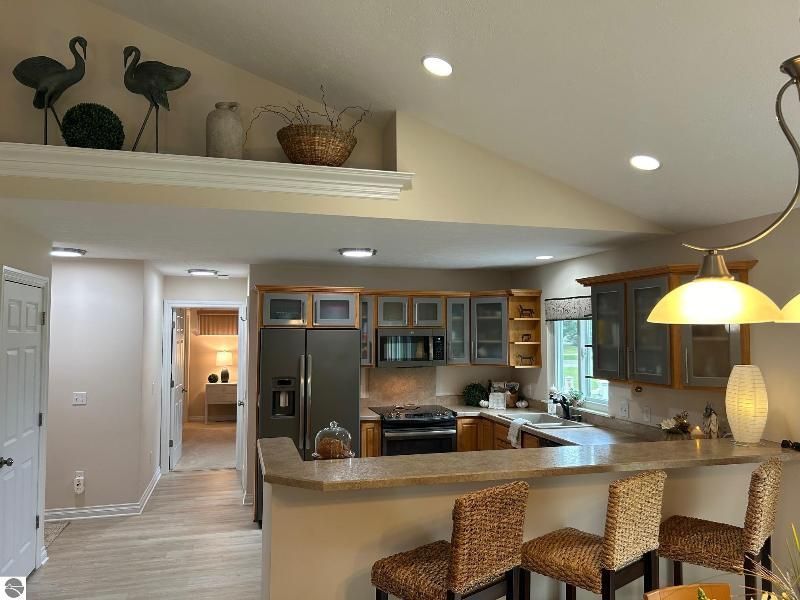 A kitchen with a stove , refrigerator , microwave and stools.