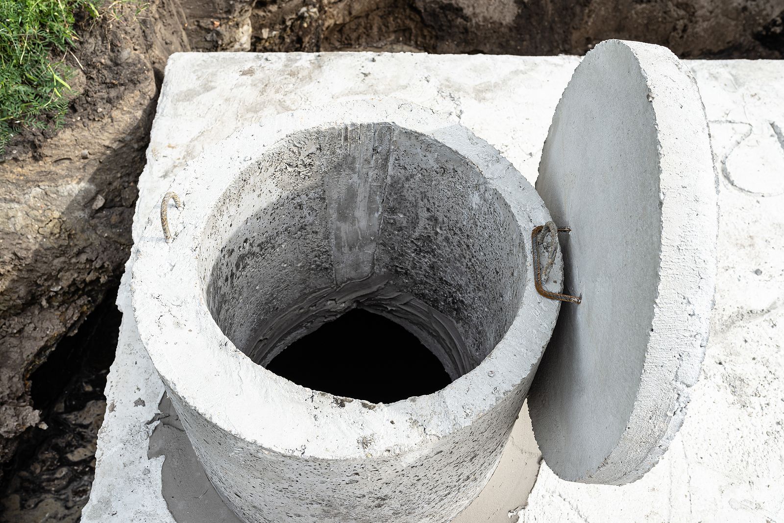A concrete toilet with the lid open and a hole in the middle