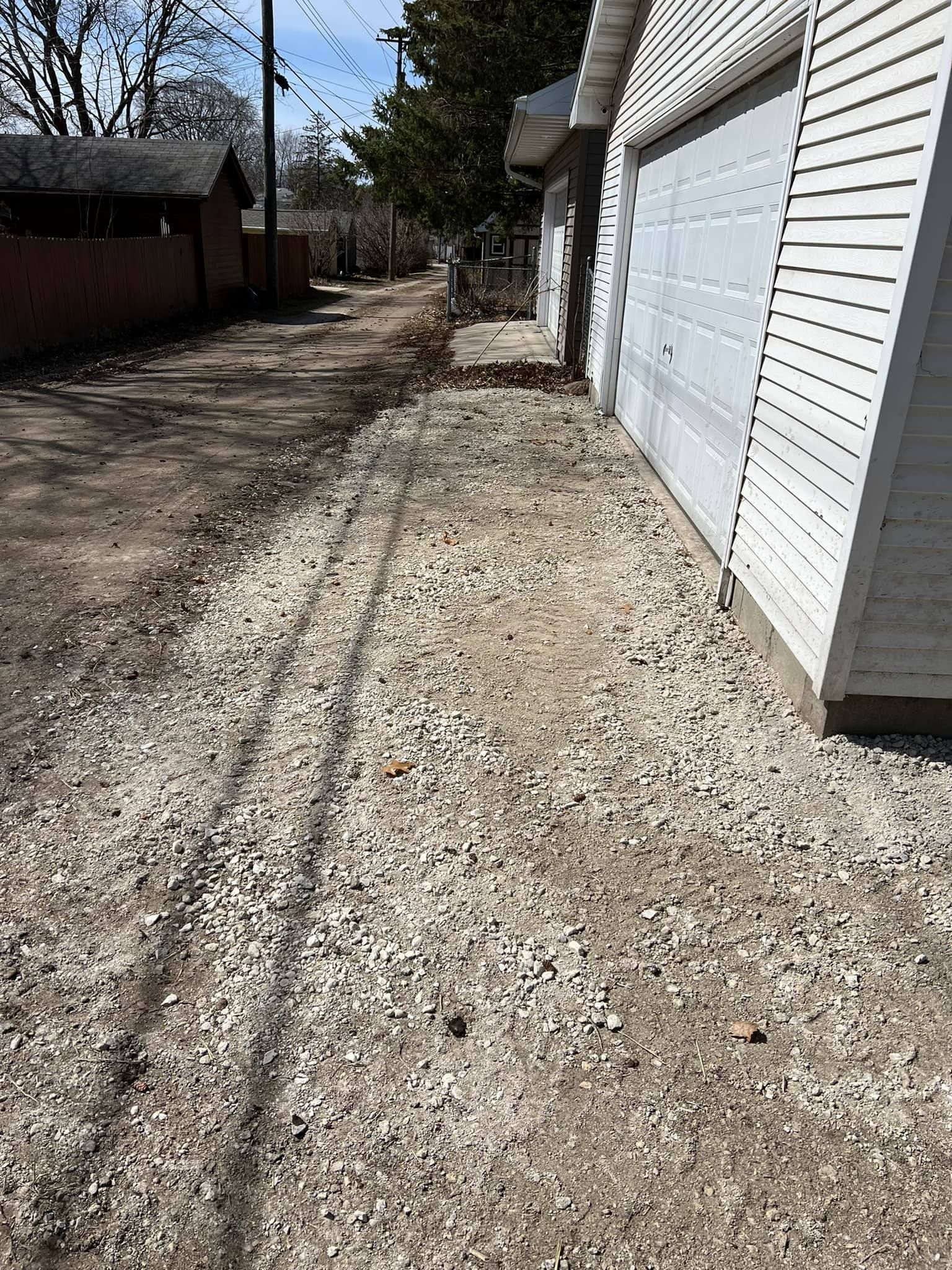 A gravel driveway leading to a garage next to a house.