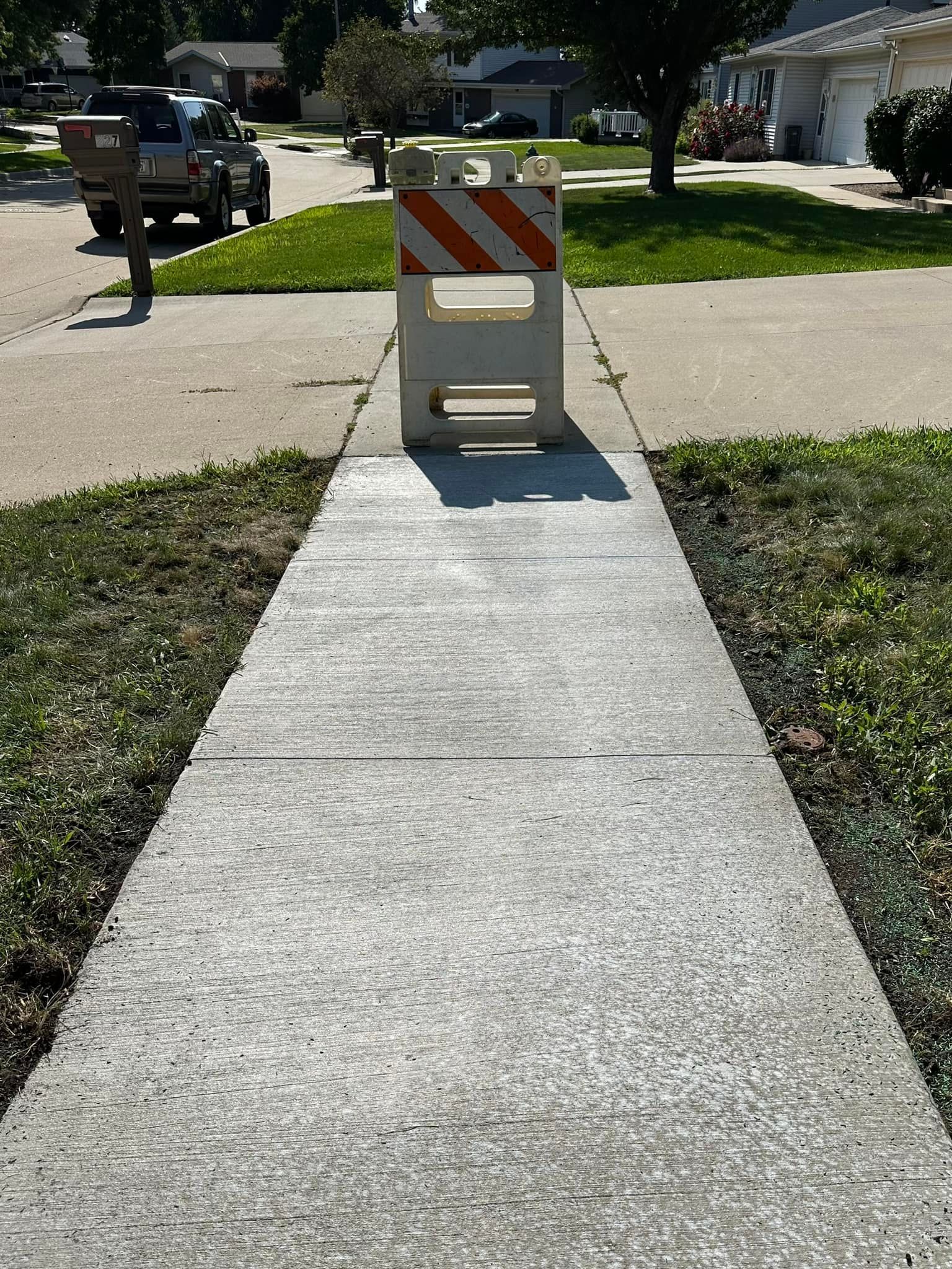 A sidewalk with a white and orange barricade on it