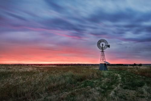 Windmill is Sitting in the Middle of a Field at Sunset — Grants Express in Orange, NSW
