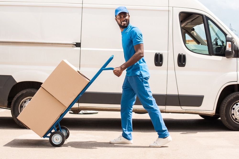 Delivery Man is Pushing a Cart With Boxes in Front of a Van — Grants Express in Forbes, NS
