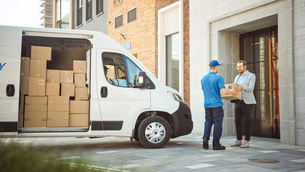 Delivery Man is Handing a Box to Another Man in Front of a Van — Grants Express in Bathurst, NSW