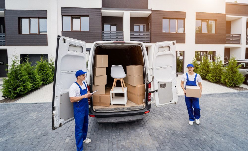 Two Movers Are Loading a Van With Boxes in Front of a House — Grants Express in Pemulwuy, NSW