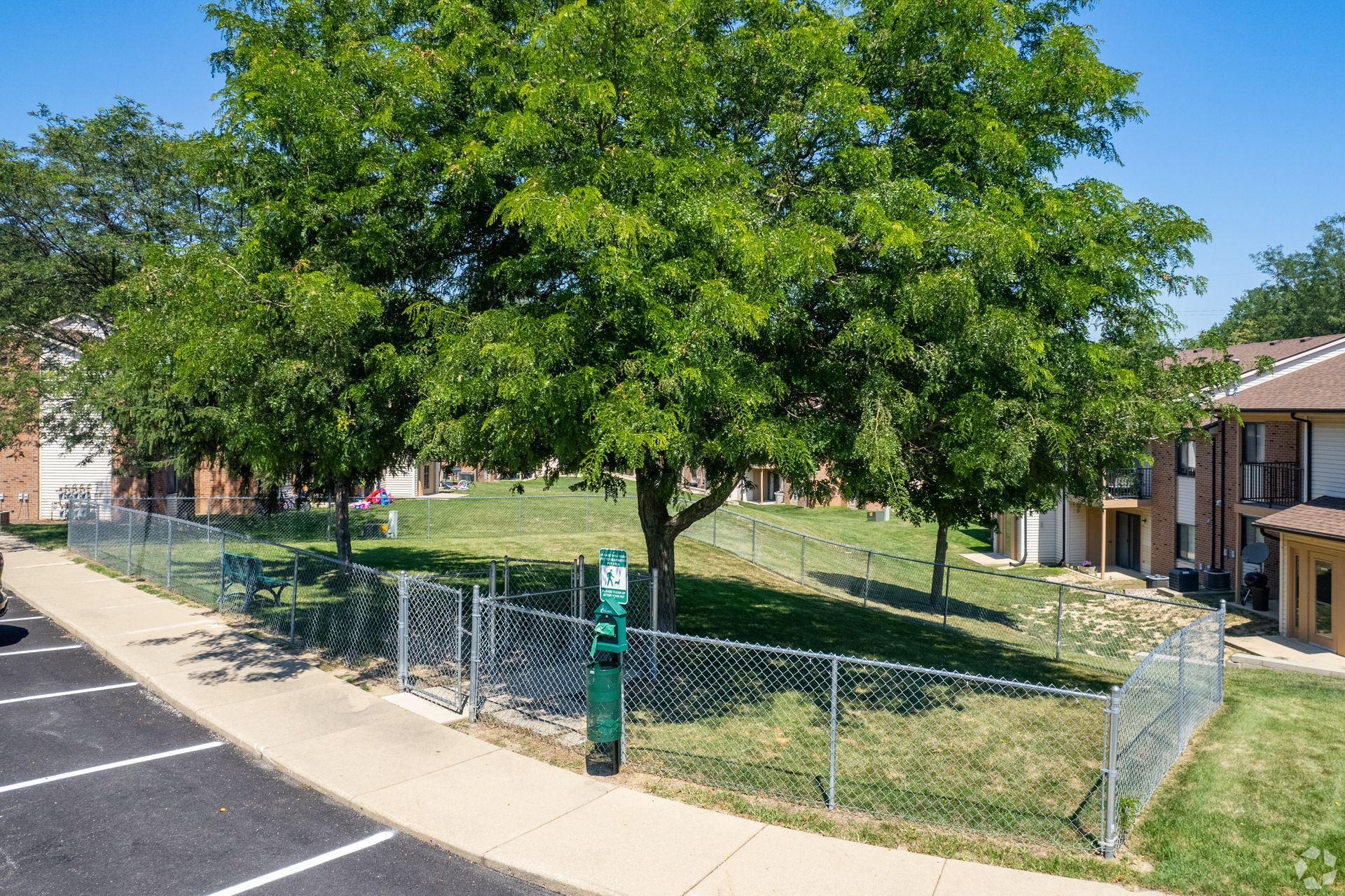 A parking lot with a chain link fence and a tree in the middle.