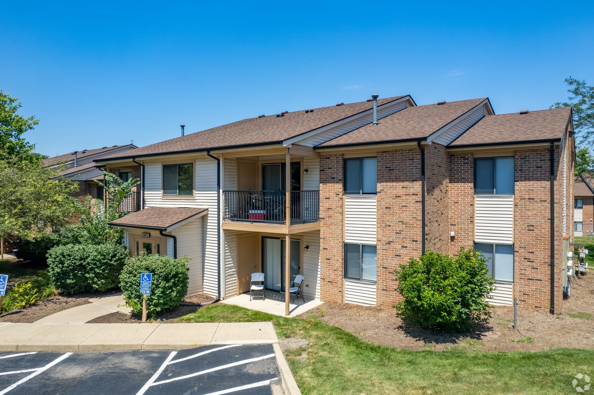A large brick apartment building with a parking lot in front of it.