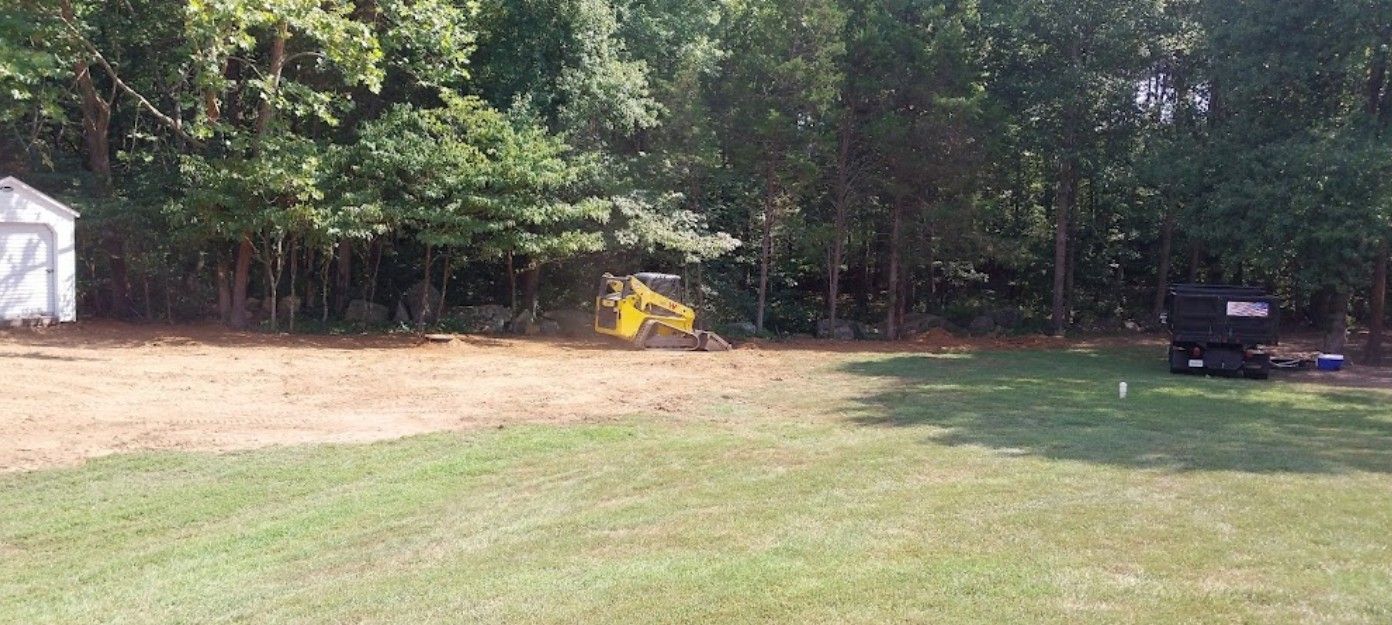 A yellow tractor is sitting in the middle of a grassy field.