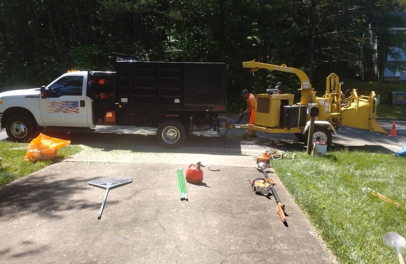 A truck is parked in a driveway next to a tree chipper.