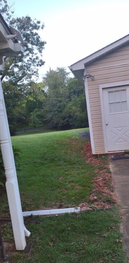 A white gutter is sitting on the side of a house next to a garage.