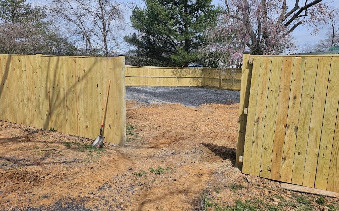A wooden fence is sitting in the middle of a dirt field.
