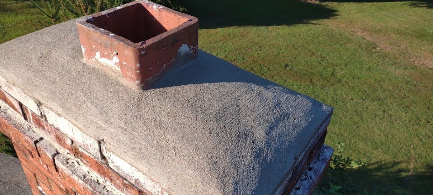 A brick chimney sitting on top of a concrete post in a yard.