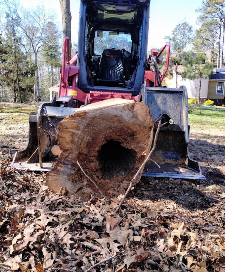 A large tree stump is being removed by a bulldozer