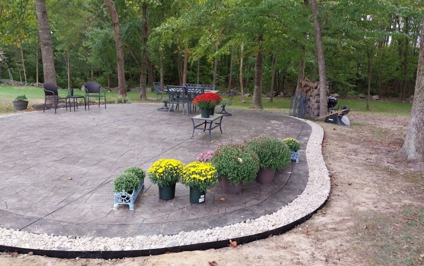A patio with flowers in pots and a table and chairs in the background.